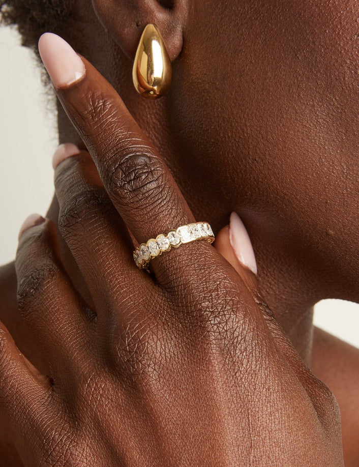 Close-up of a hand with a gold ring and earring.