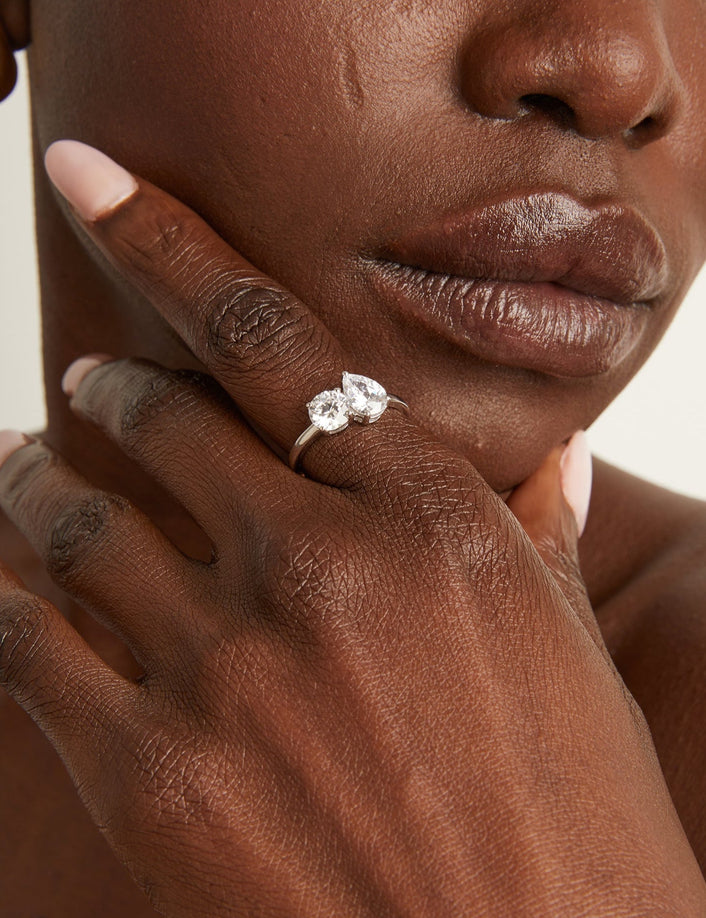 Close up of a toi et moi diamond ring on woman with a white background.
