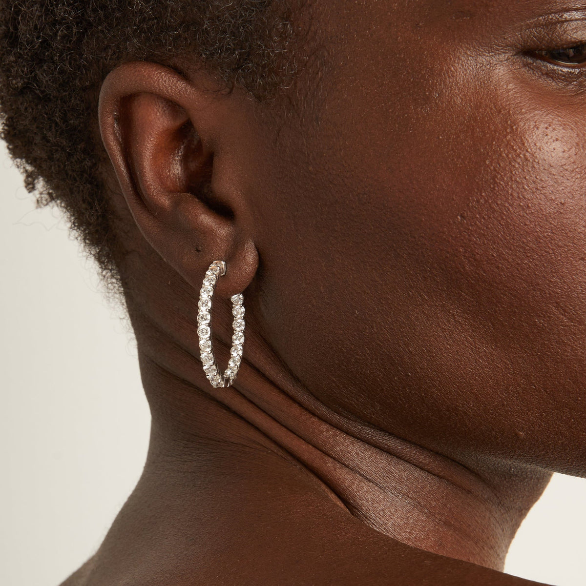 Model.  close up of woman wearing diamond hoop earring 