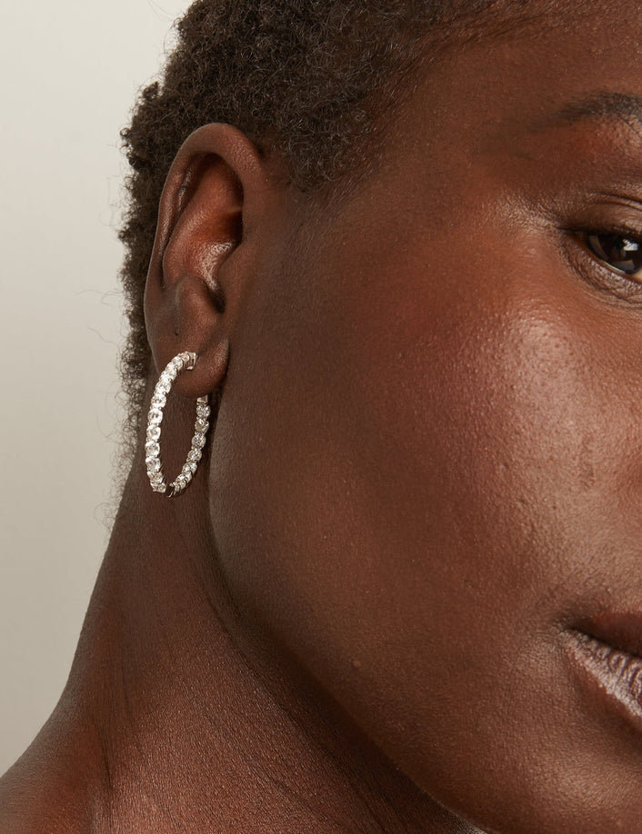 close up of woman wearing diamond hoop earring 