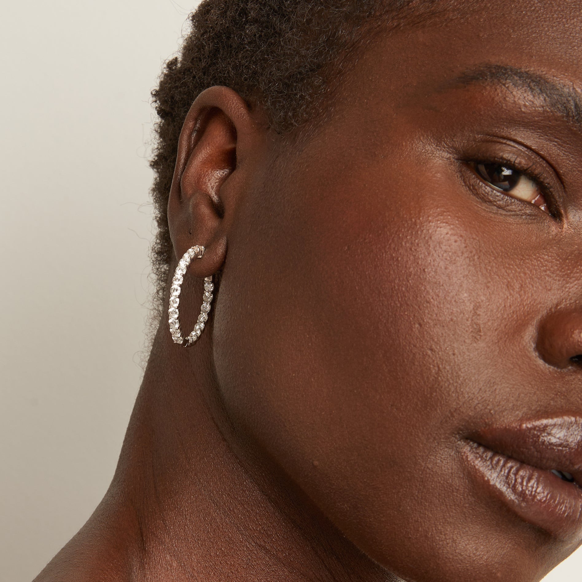 close up of woman wearing diamond hoop earring 