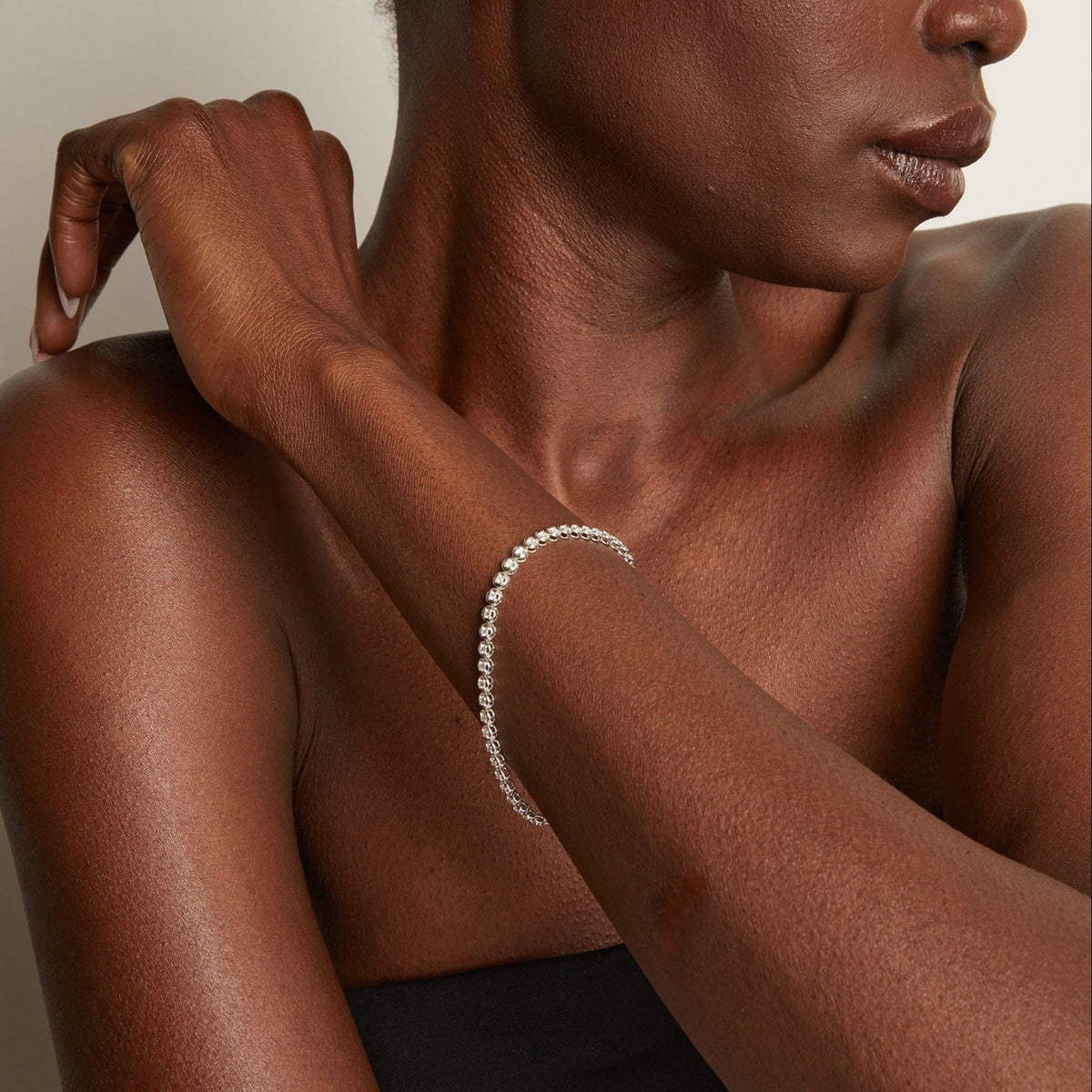 Model. Close-up of a person wearing a silver bracelet on a neutral background