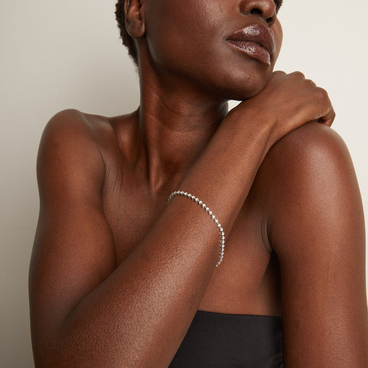 Woman wearing a delicate bracelet on her wrist against a neutral background