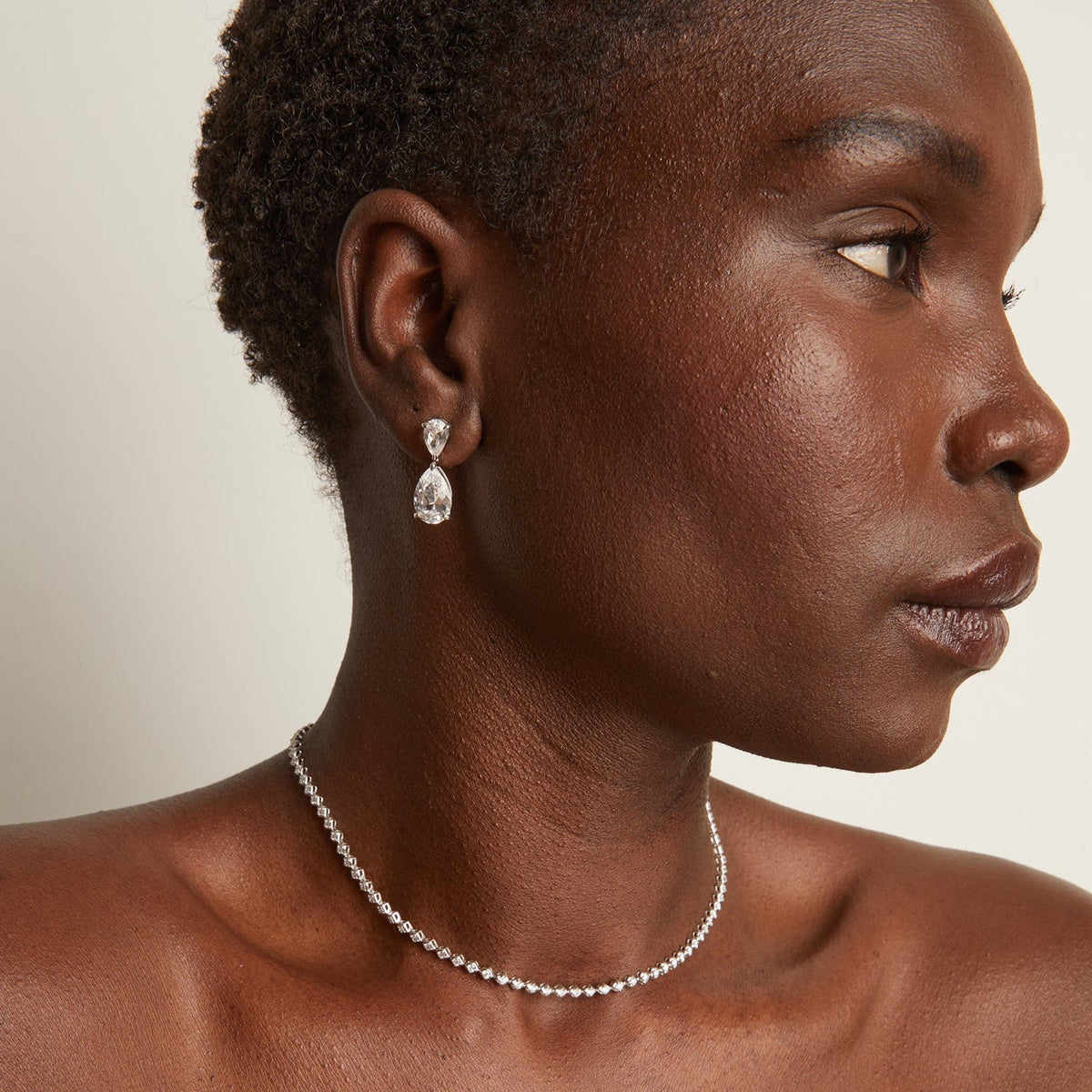 Model. Woman wearing a necklace and earring against a neutral background