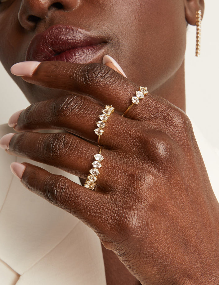 Woman wearing various rings with white sapphire gemstones.