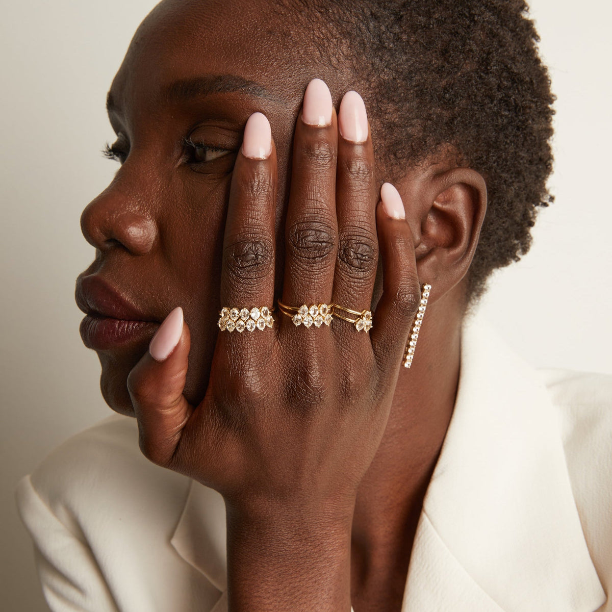 Model. Woman wearing various rings with white sapphire gemstones.