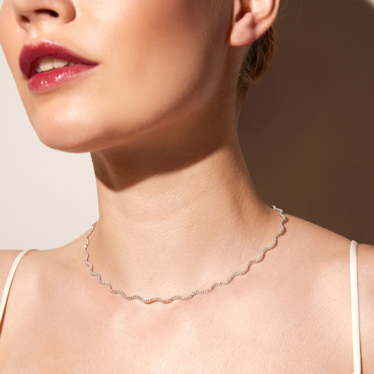 Model. Woman wearing wavy tennis necklace on neutral background