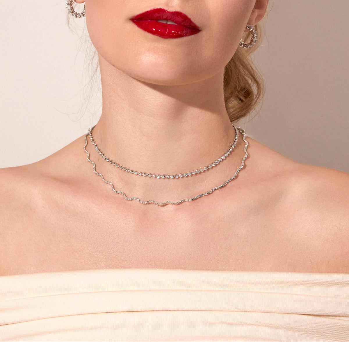 Model. Woman wearing two tennis necklaces on neutral background