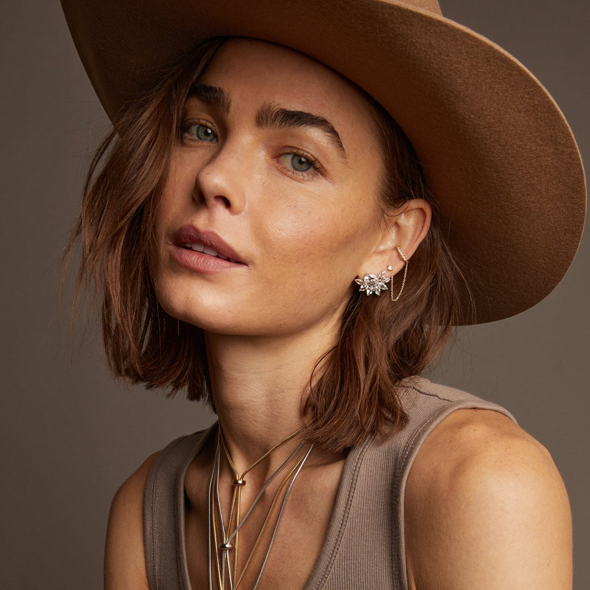 Model. Woman wearing various jewelry on beige background