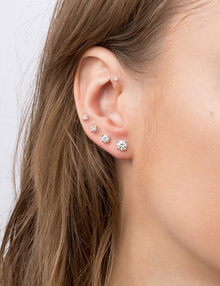 Woman wearing different sized diamond stud earrings 