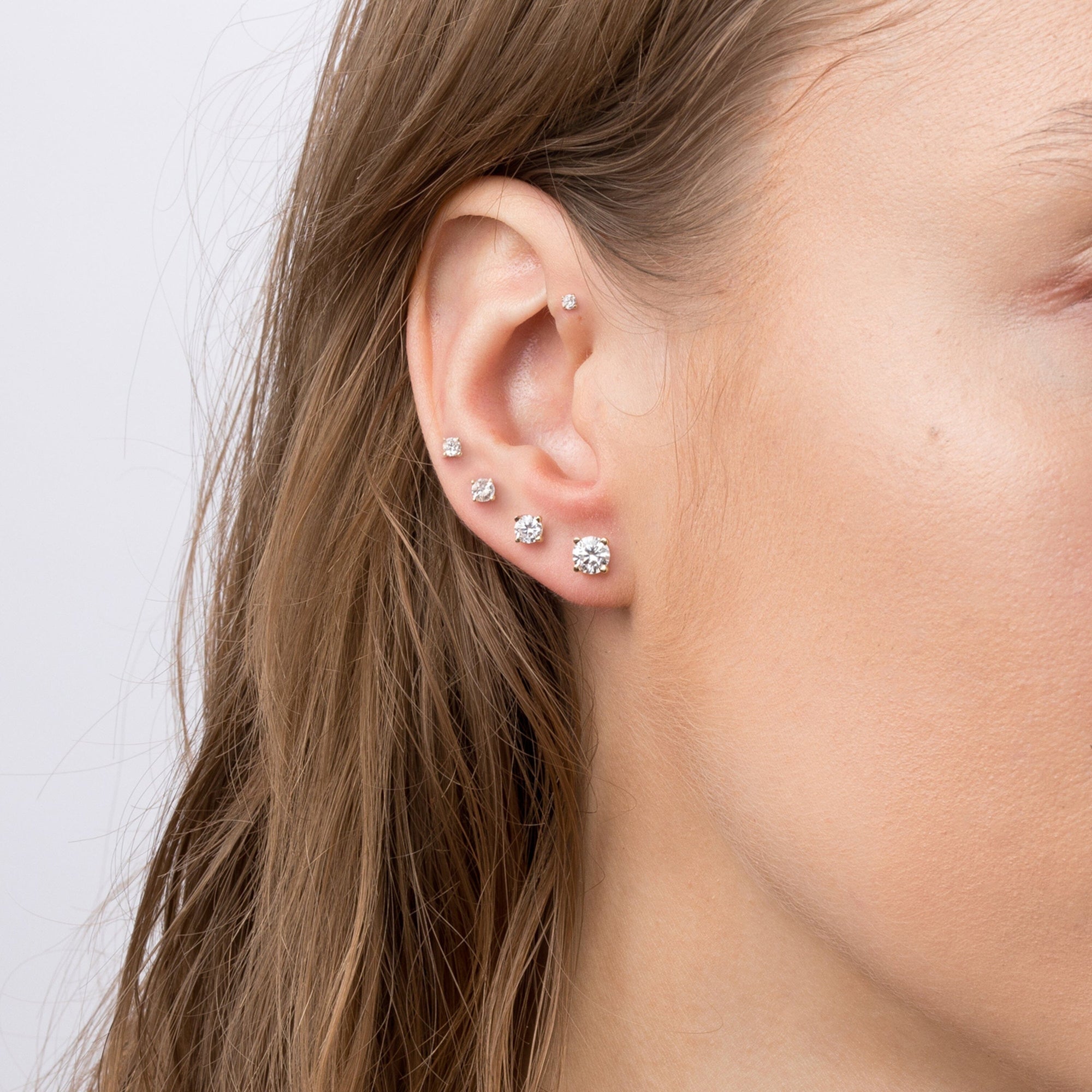 Woman wearing different sized diamond stud earrings 