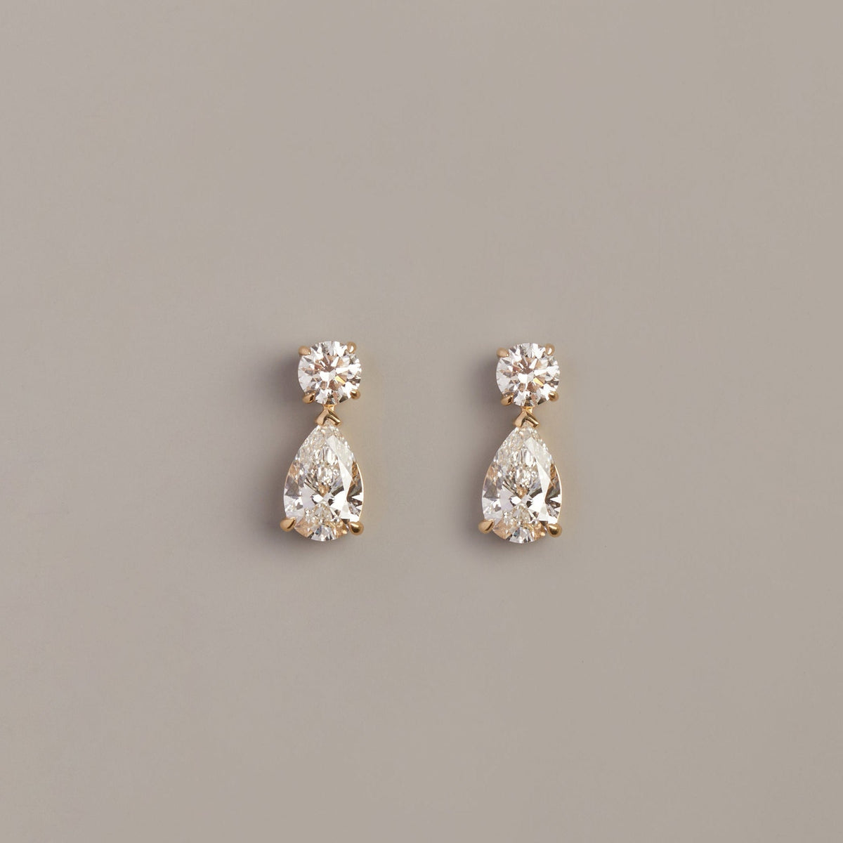 Model. Pair of teardrop-shaped diamond earrings on a gray background