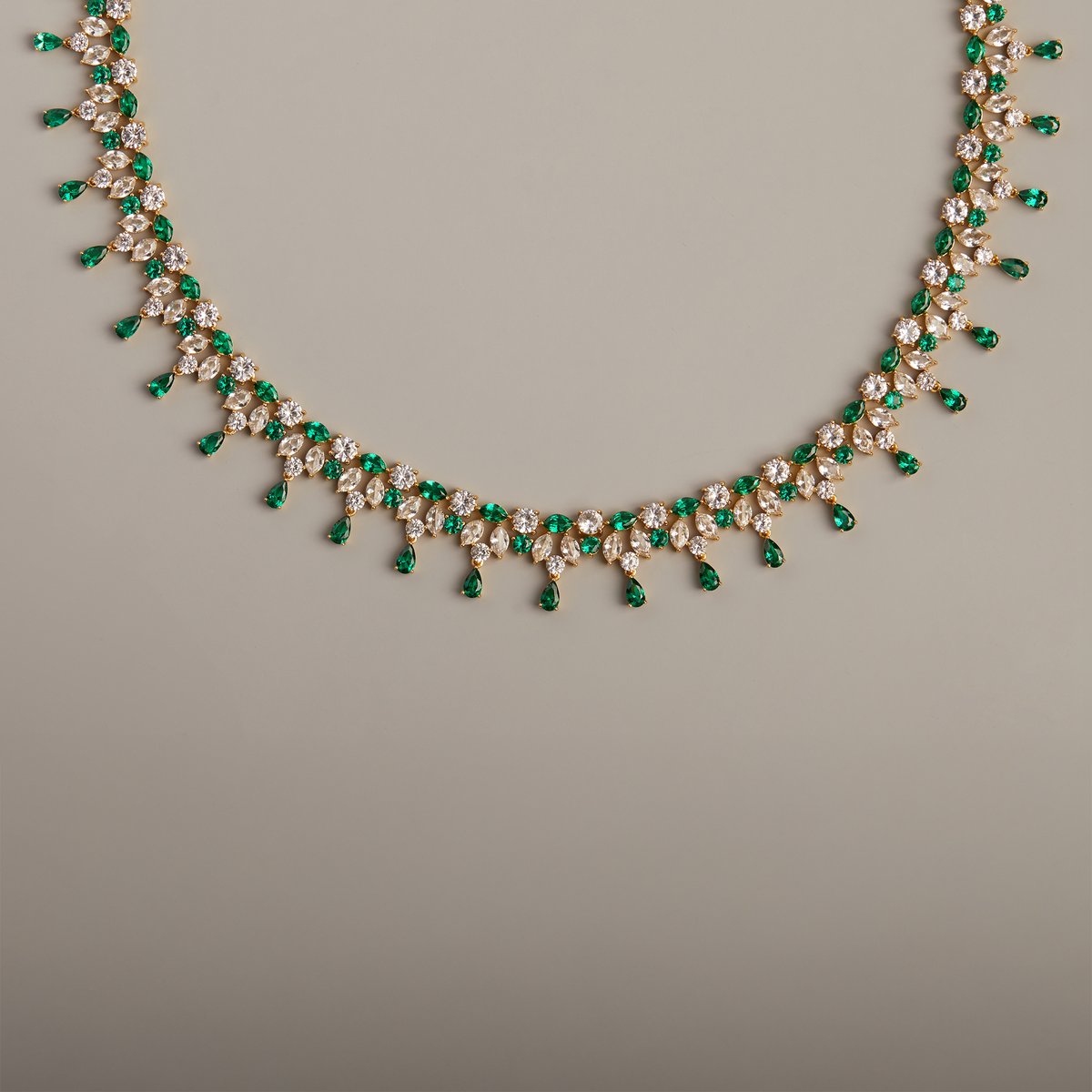 Model. Necklace with green and clear stones on a gray background