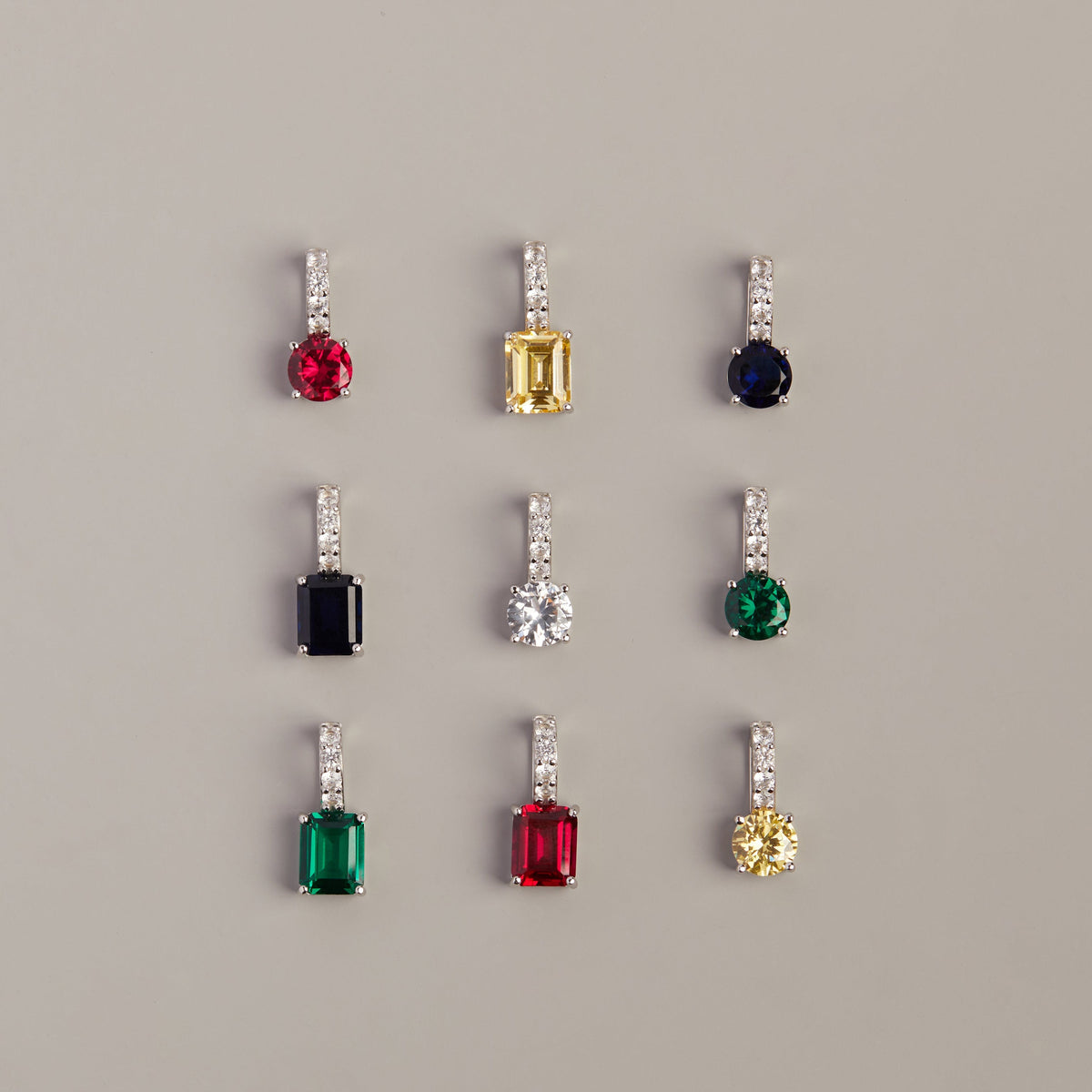 Model. Set of earrings with colored gemstones on a gray background
