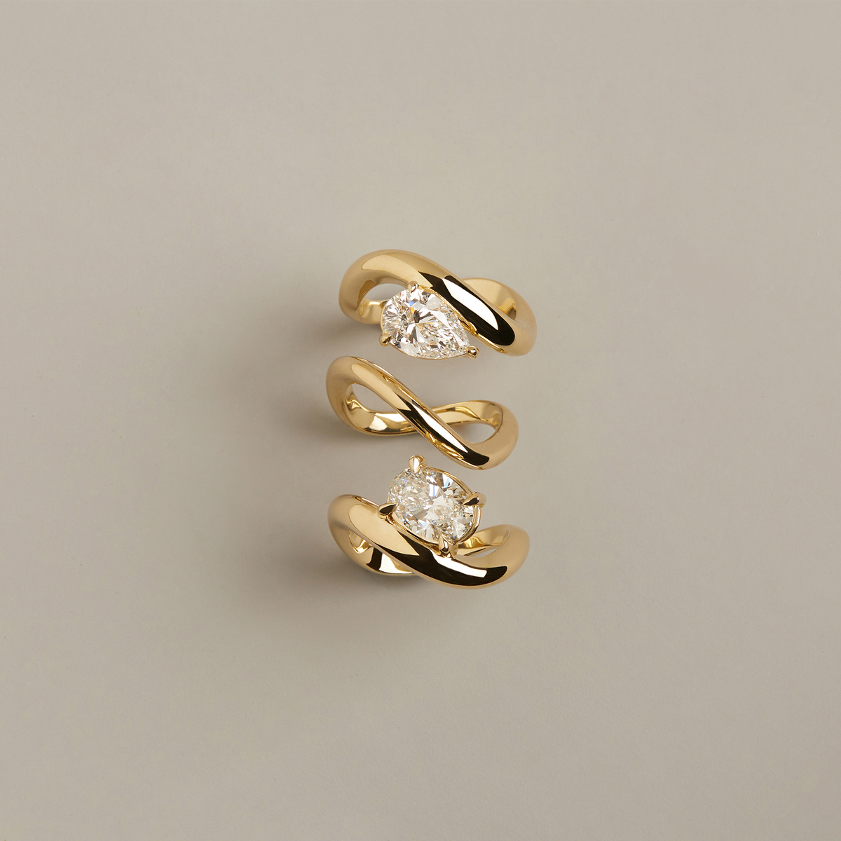 Model. Gold spiral earrings with diamond-like stones on a beige background