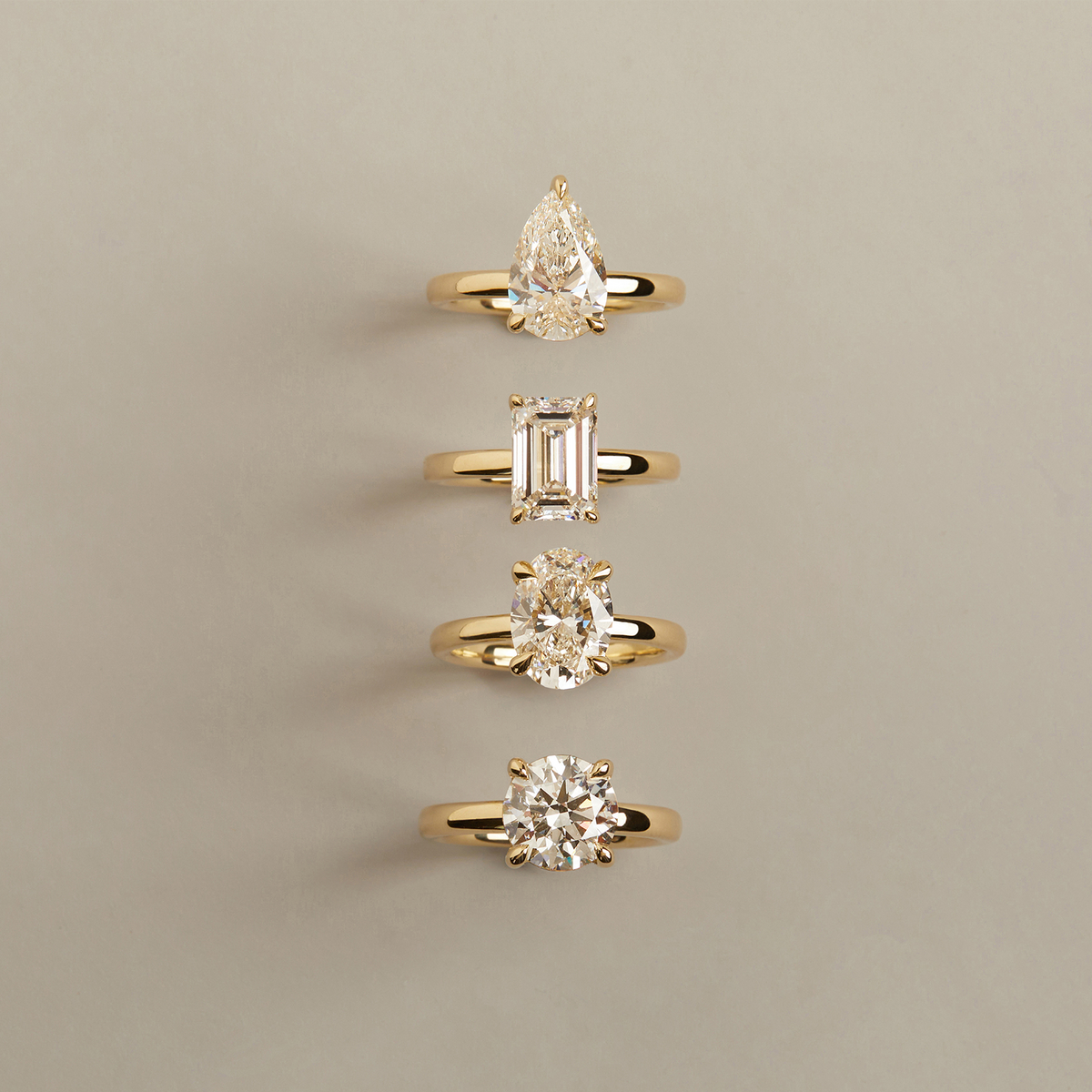 Model. Set of four gold rings with different diamond shapes on a beige background