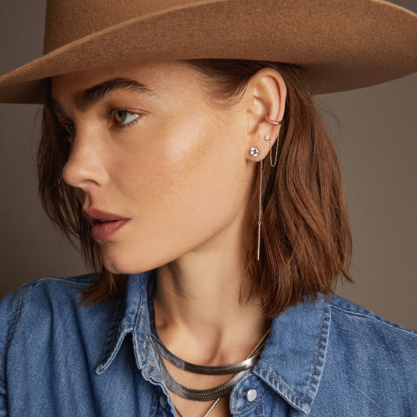 Model. Woman wearing various jewelry on beige background
