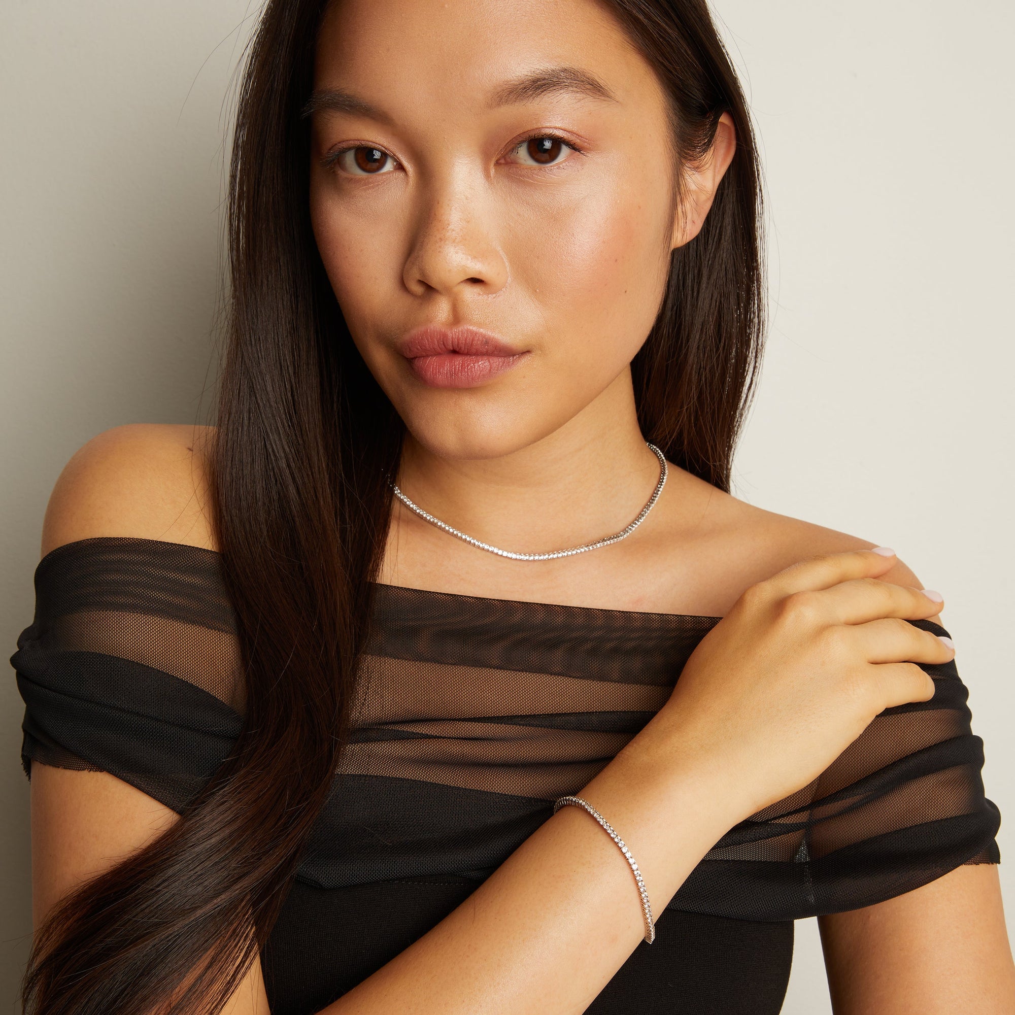 Model. Woman wearing a black sheer top with a plain background