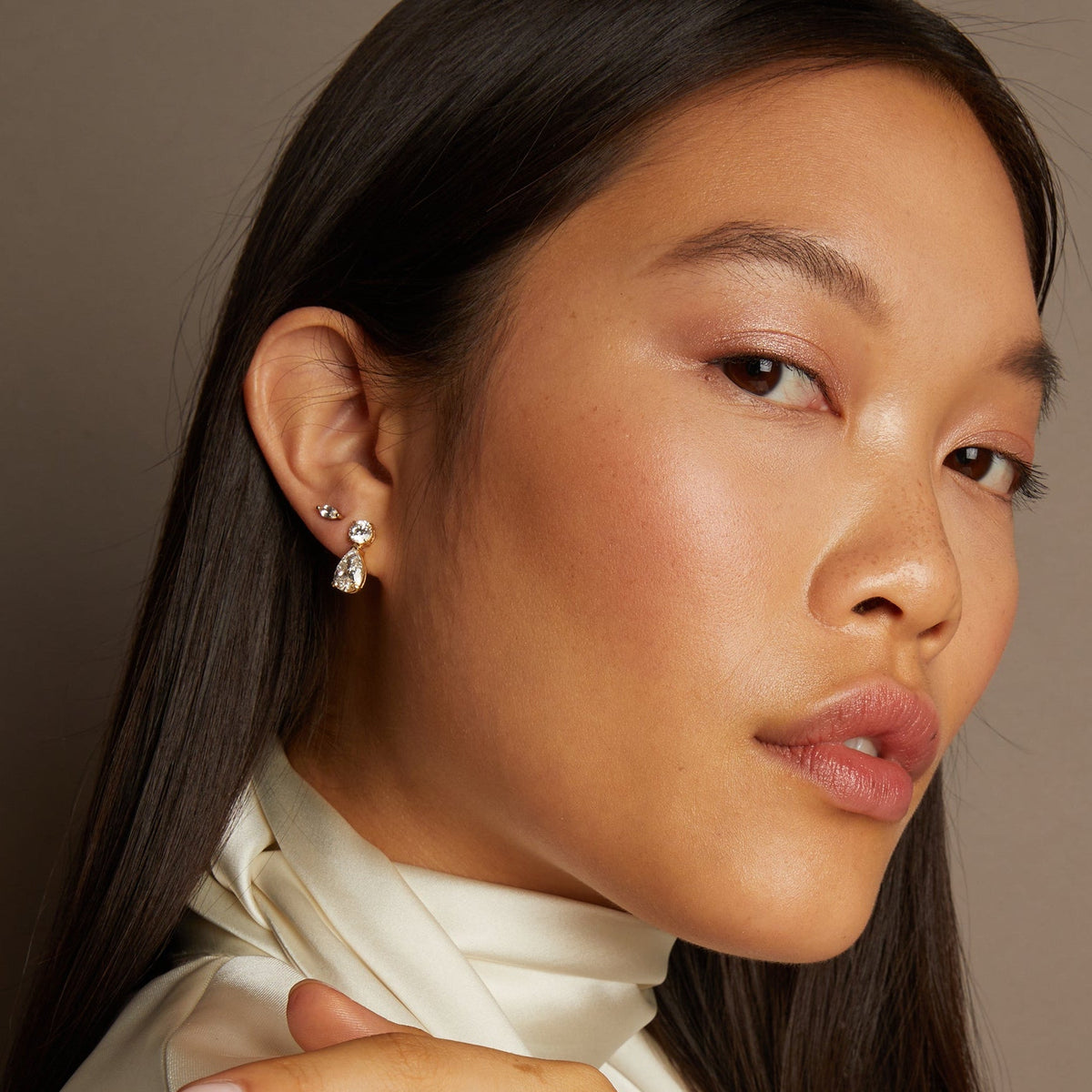 Close-up of a woman wearing earrings with a neutral background