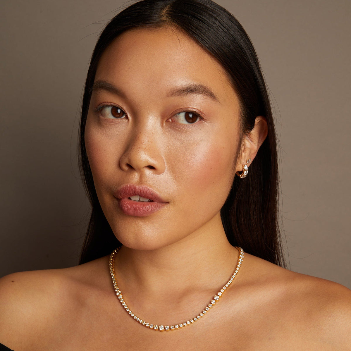 Model. Woman wearing a pearl necklace against a neutral background