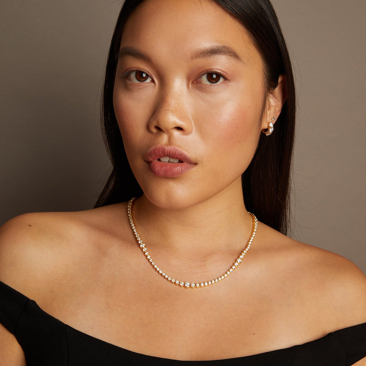 Model. Woman wearing a pearl necklace against a neutral background