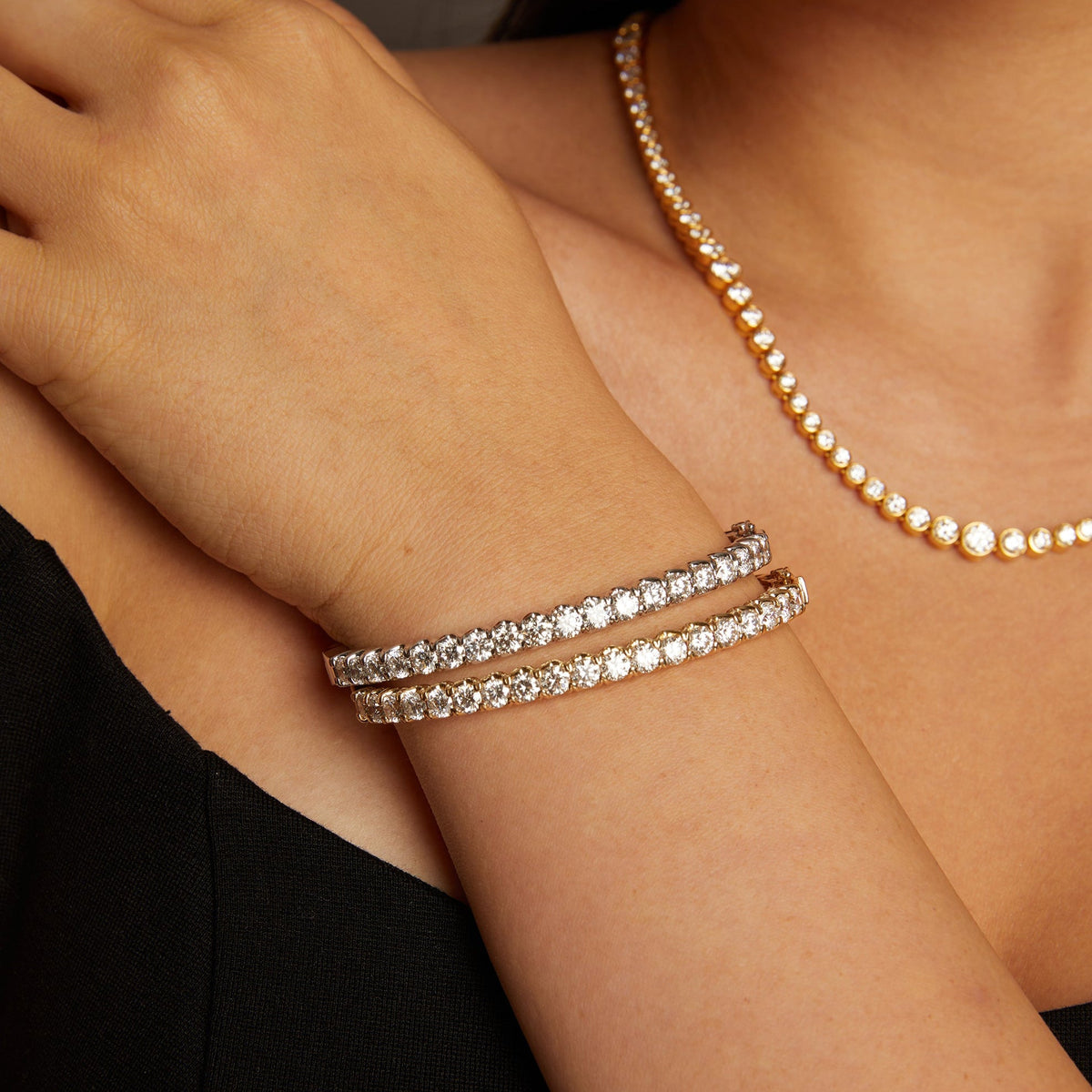 Model. Close-up of a person wearing two silver bracelets on a dark background