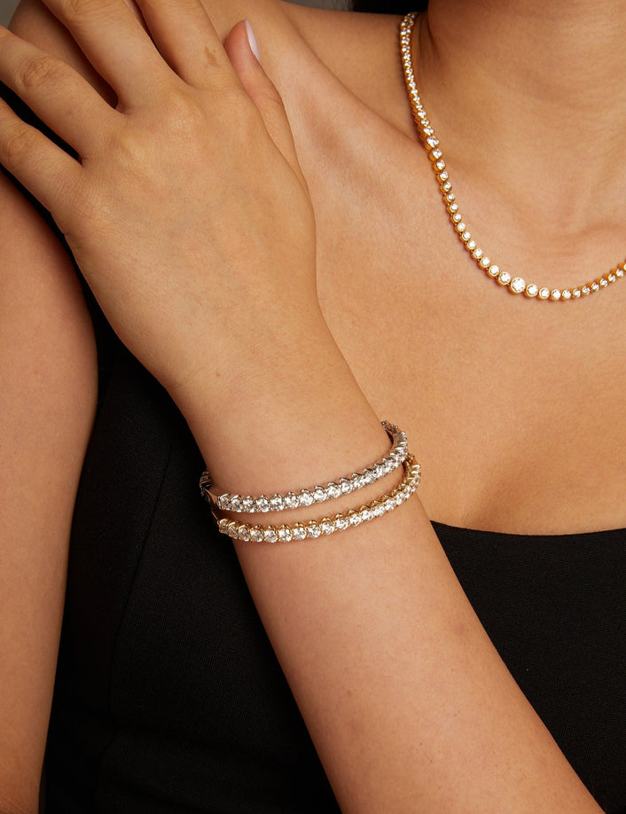 Model. Close-up of a person wearing a gold necklace and pearl bracelets on a neutral background