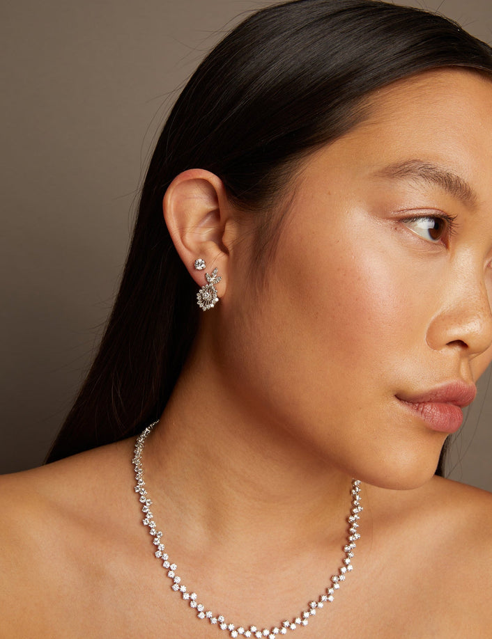 Model. Woman wearing a necklace and earrings against a neutral background