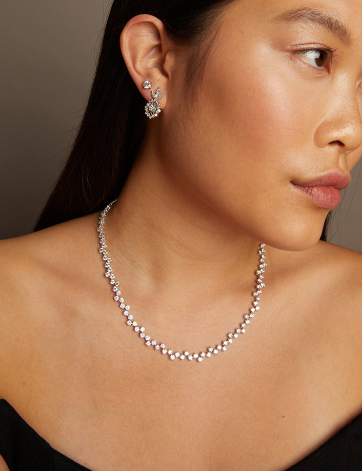 Model. Woman wearing a necklace and earrings against a neutral background