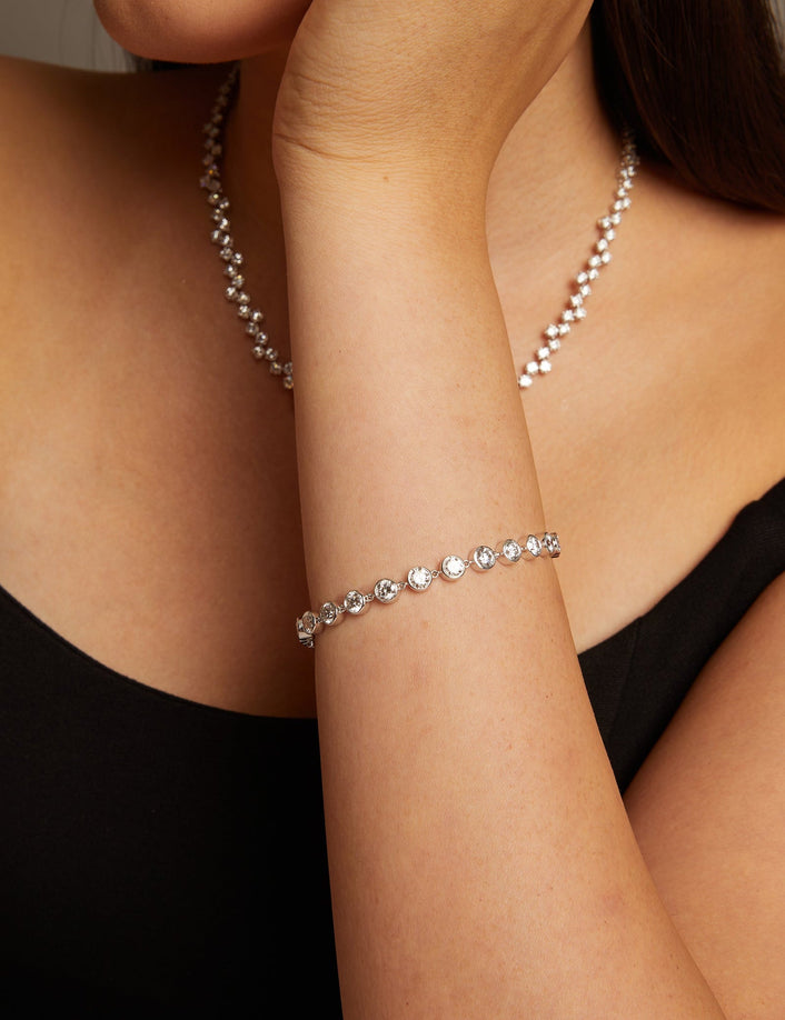 Model. Woman wearing a pearl necklace and bracelet against a neutral background