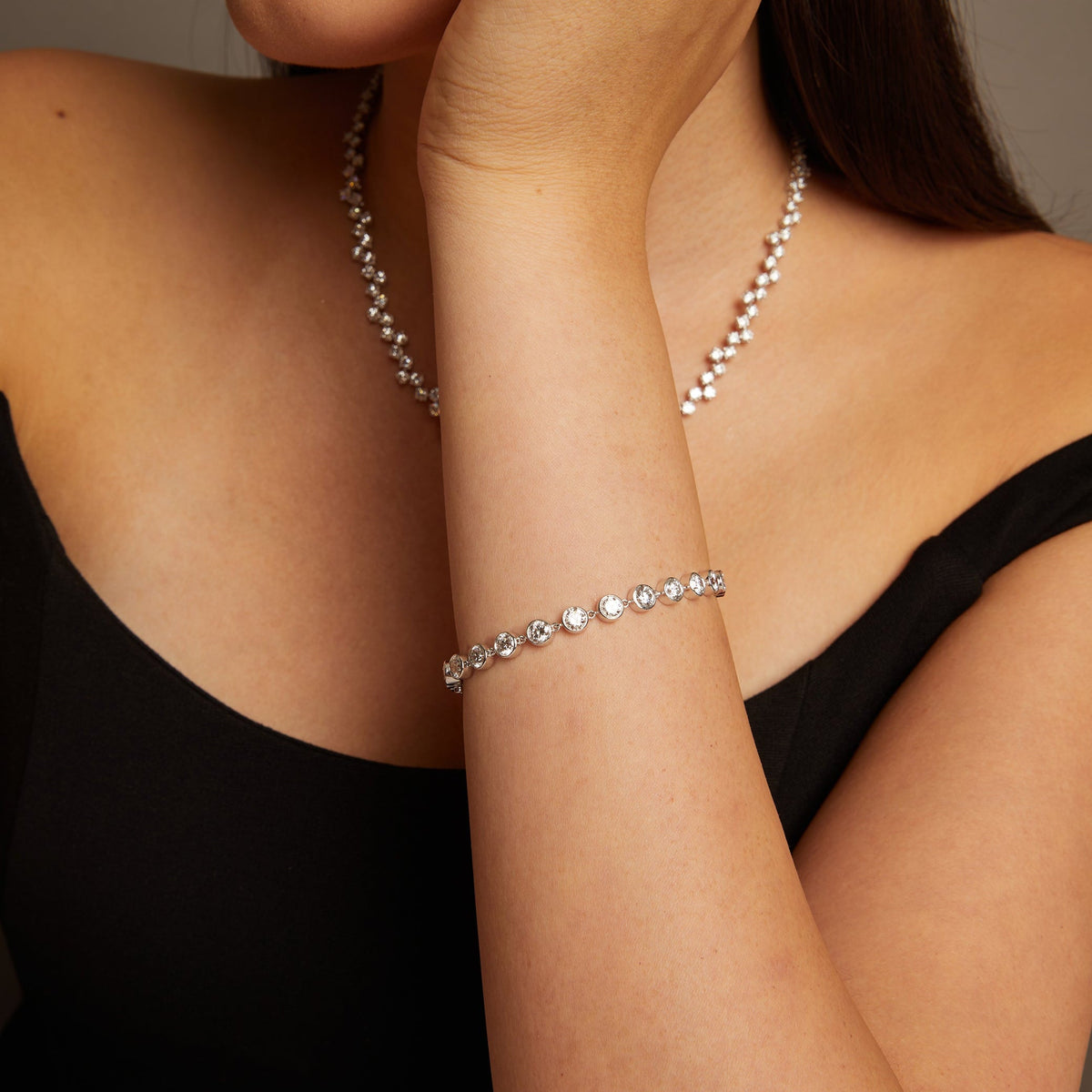 Model. Woman wearing a pearl necklace and bracelet against a neutral background