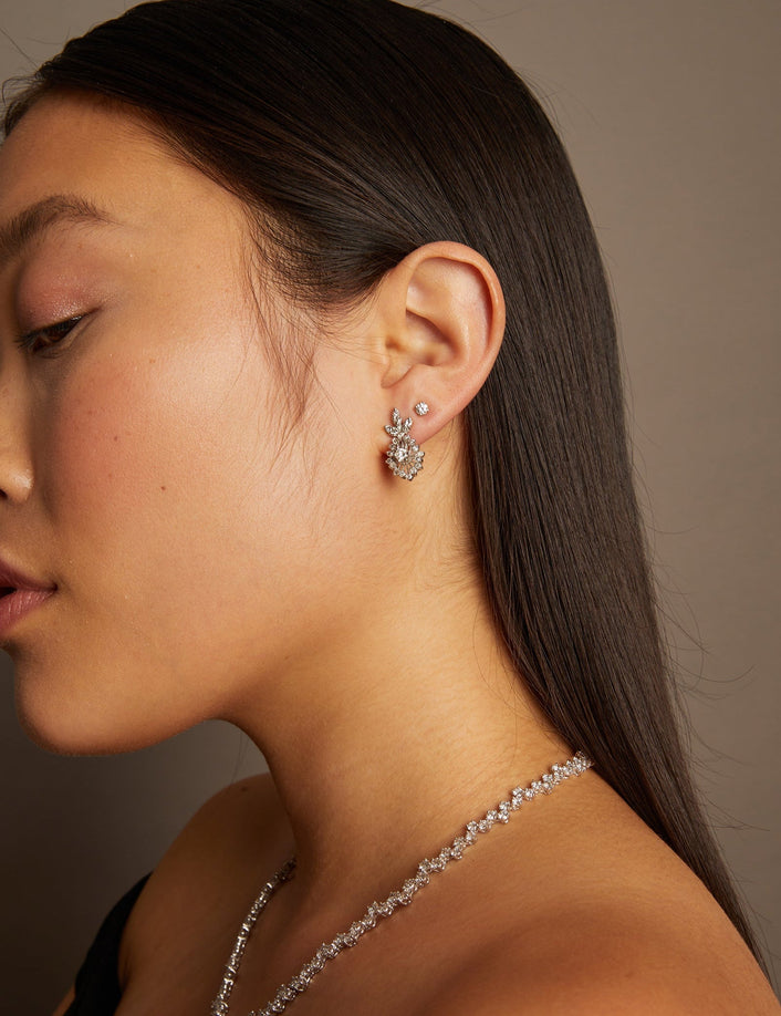 Model. Woman wearing a diamond earring and necklace against a neutral background