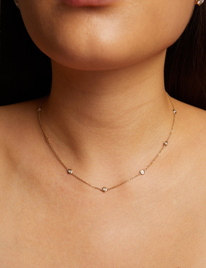 Model. Close-up of a person wearing a delicate necklace with a neutral background