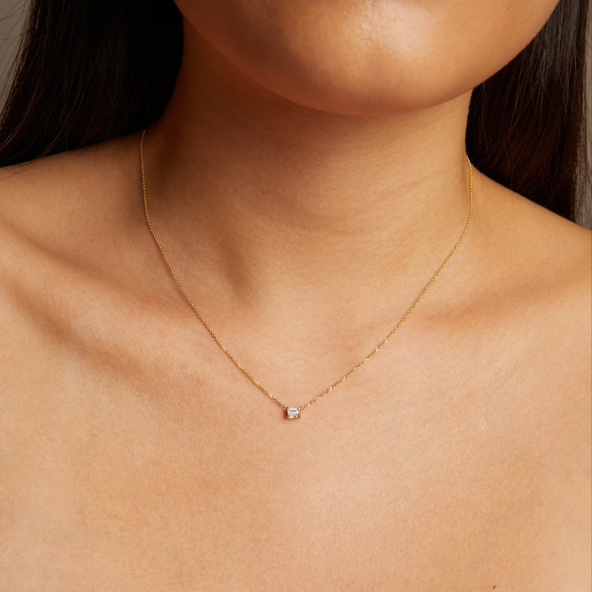 Model. Gold necklace with a small diamond pendant on a person's neck