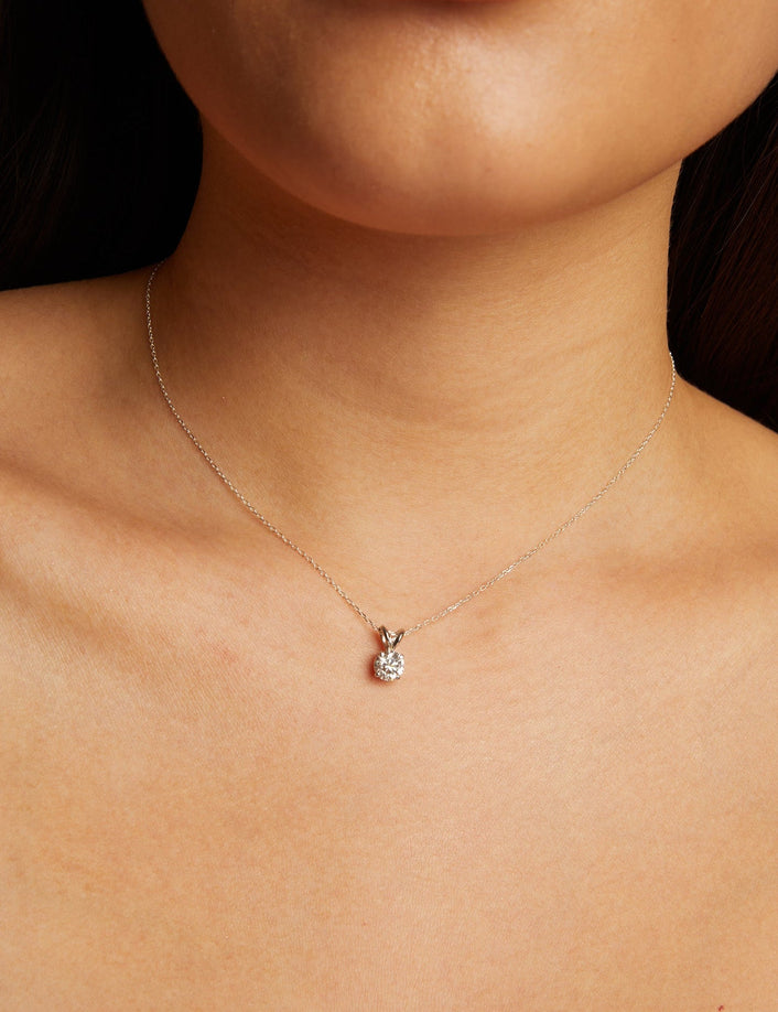 Model. Close-up of a person wearing a delicate necklace with a small pendant.