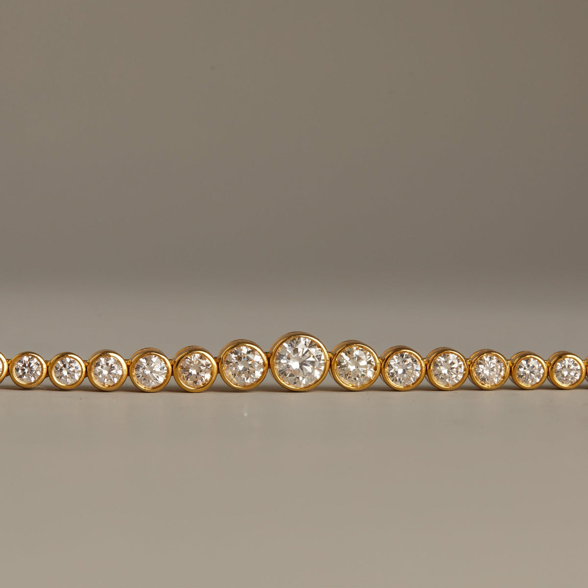 Model. Gold bracelet with clear stones on a gray background