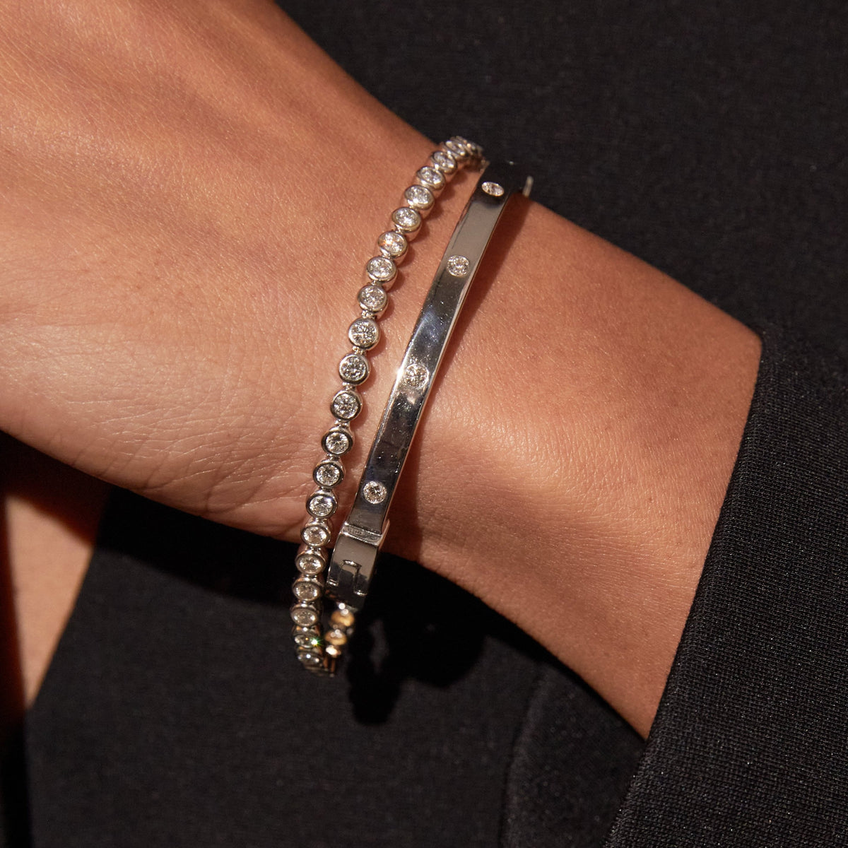 Model close up of woman wearing two silver bracelets 
