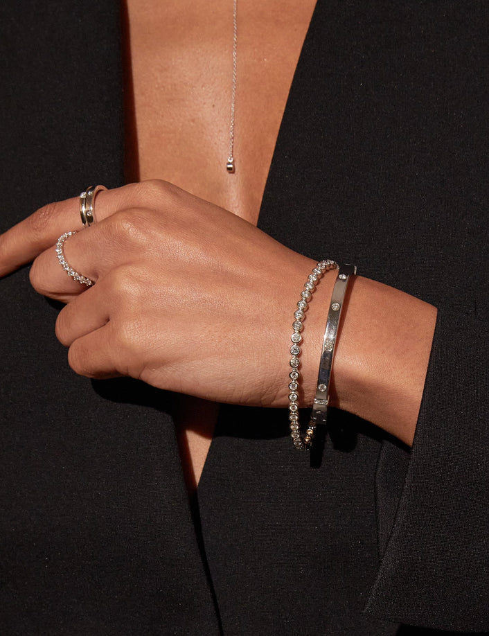 Model. Hand wearing multiple bracelets on a black background