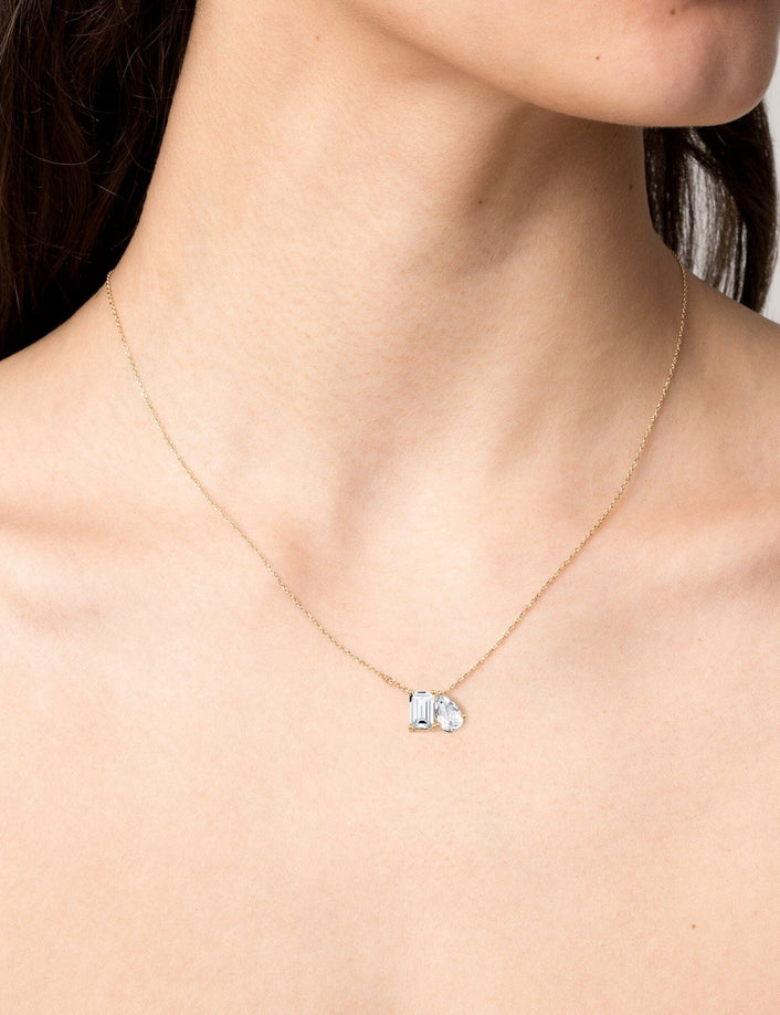 Model. Close up of woman wearing gemstone necklace on neutral background.