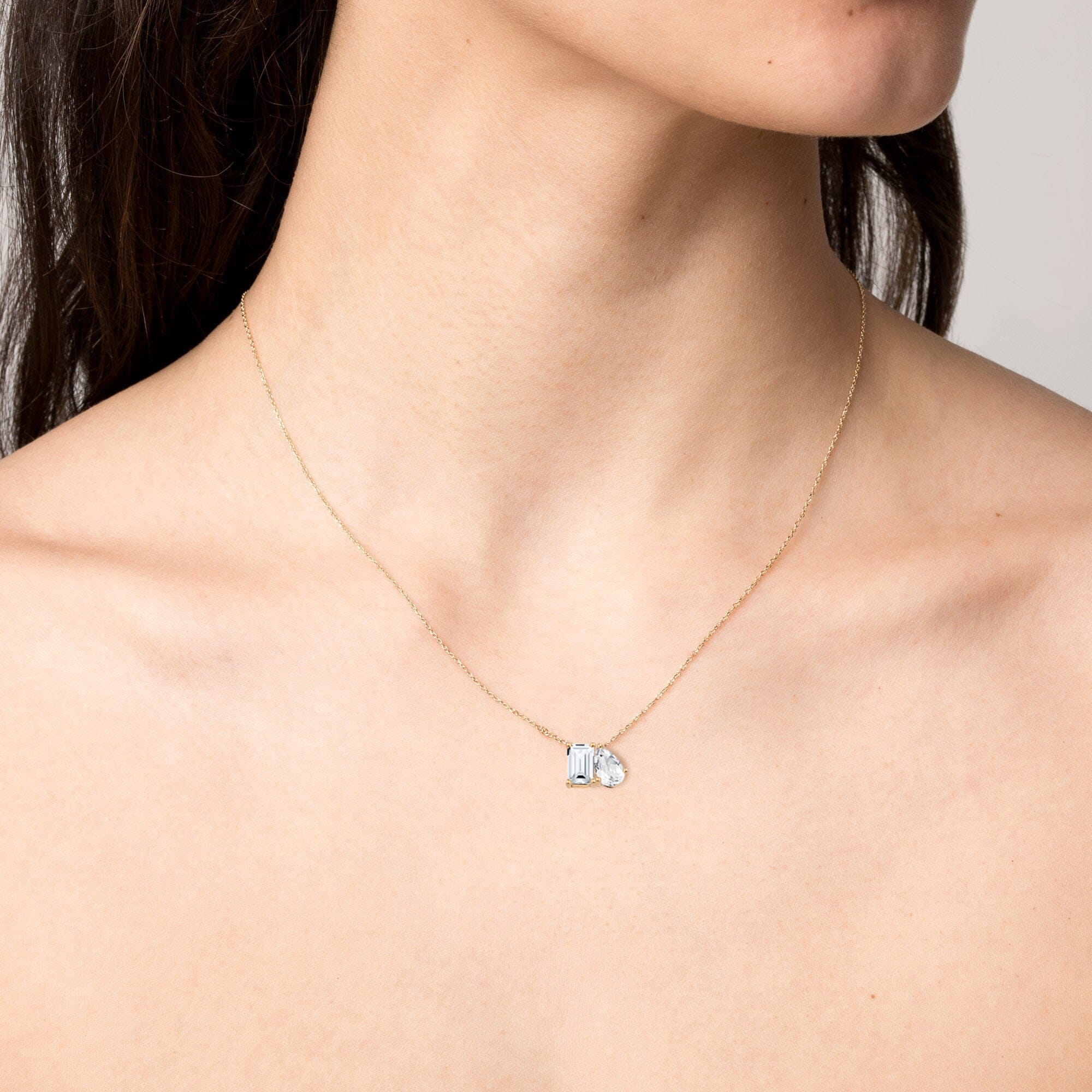 Model. Close up of woman wearing gemstone necklace on neutral background.