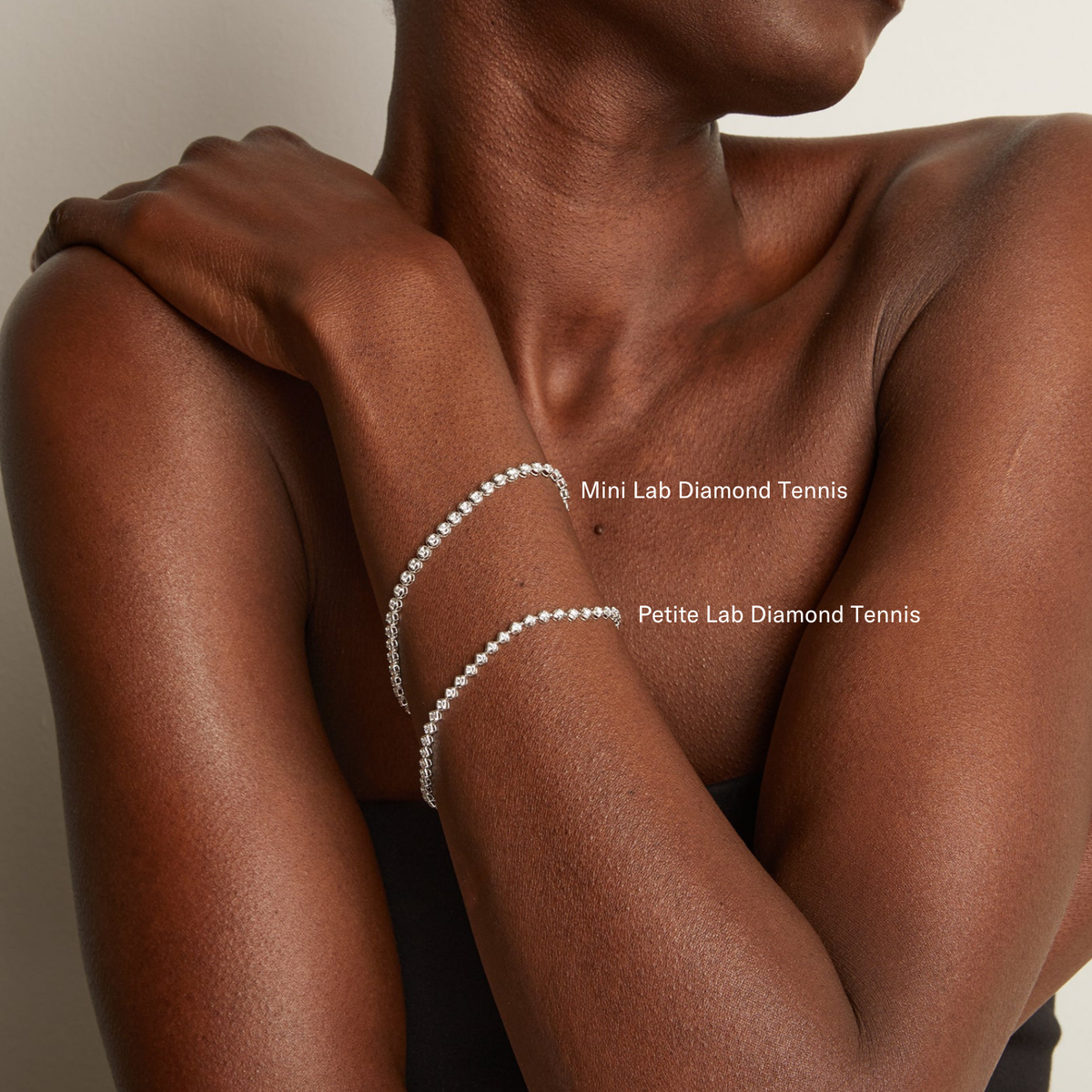 Model. Person wearing two diamond tennis bracelets on a neutral background