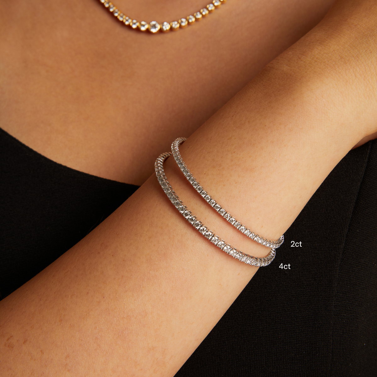 Model. Silver bracelet on a wrist with '2ct' and '4ct' labels, against a black background.