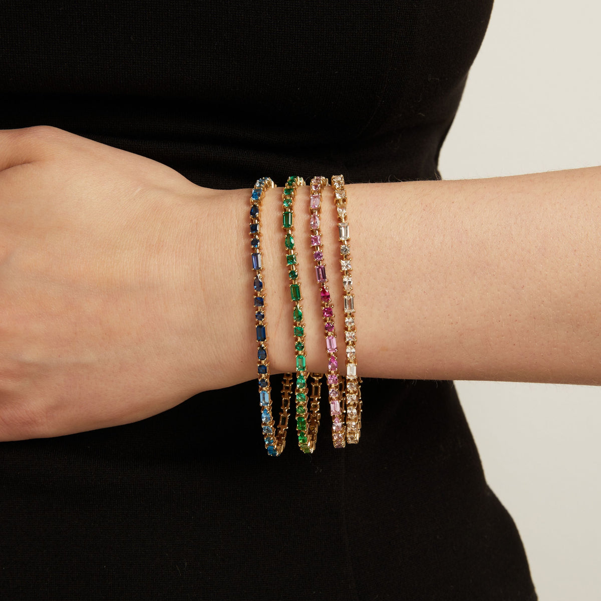 Model. Four colorful tennis bracelets on a person's wrist against a neutral background.