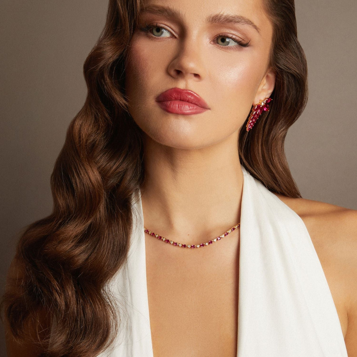 Model. Woman wearing a necklace and earrings with a neutral background