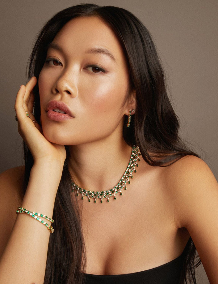 Model. Woman wearing a green necklace and bracelet against a brown background