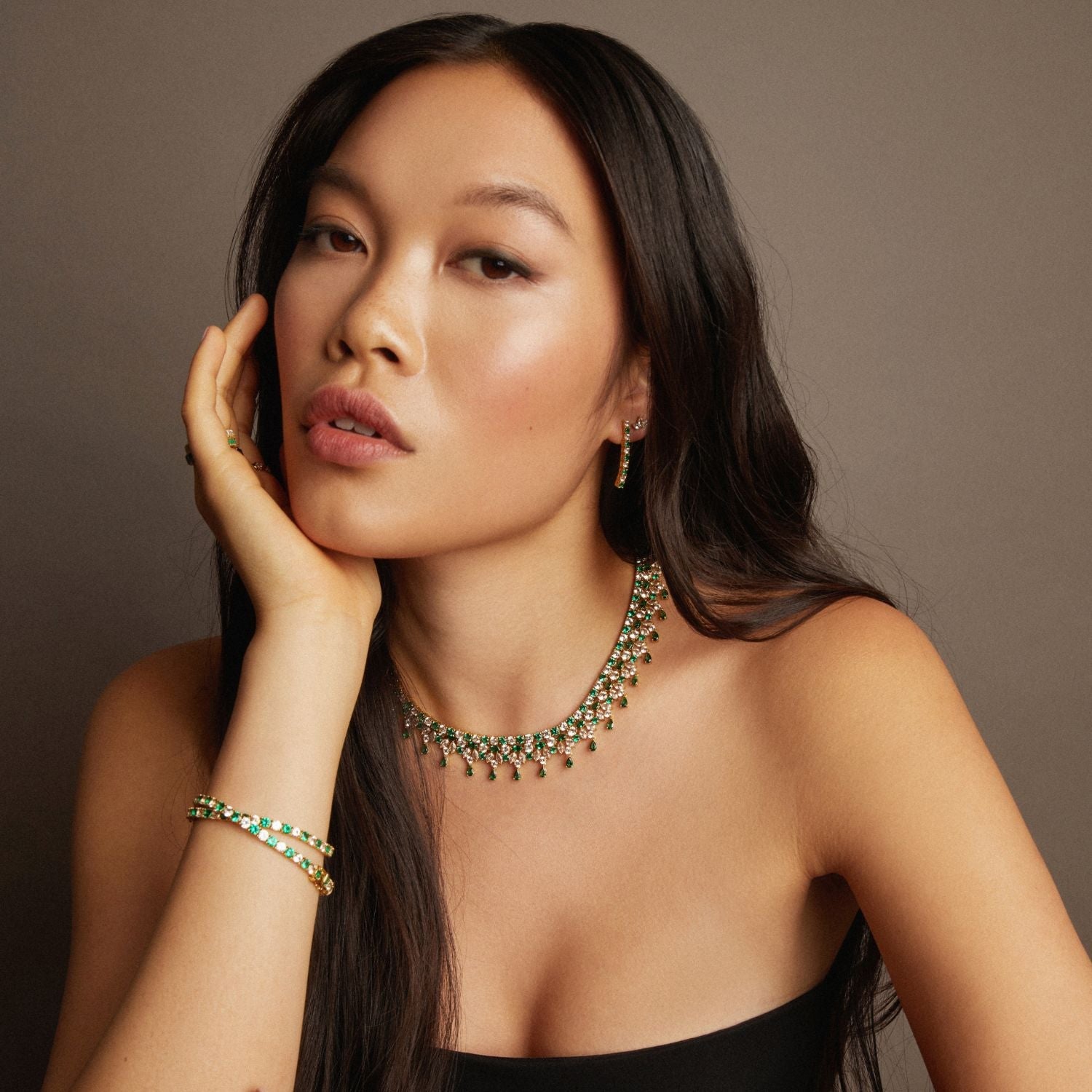 Model. Woman wearing a green necklace and bracelet against a brown background