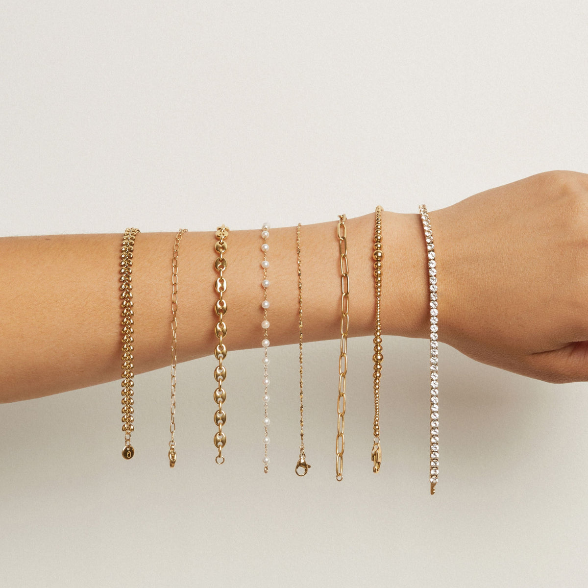Model. Multiple bracelets on a wrist against a neutral background