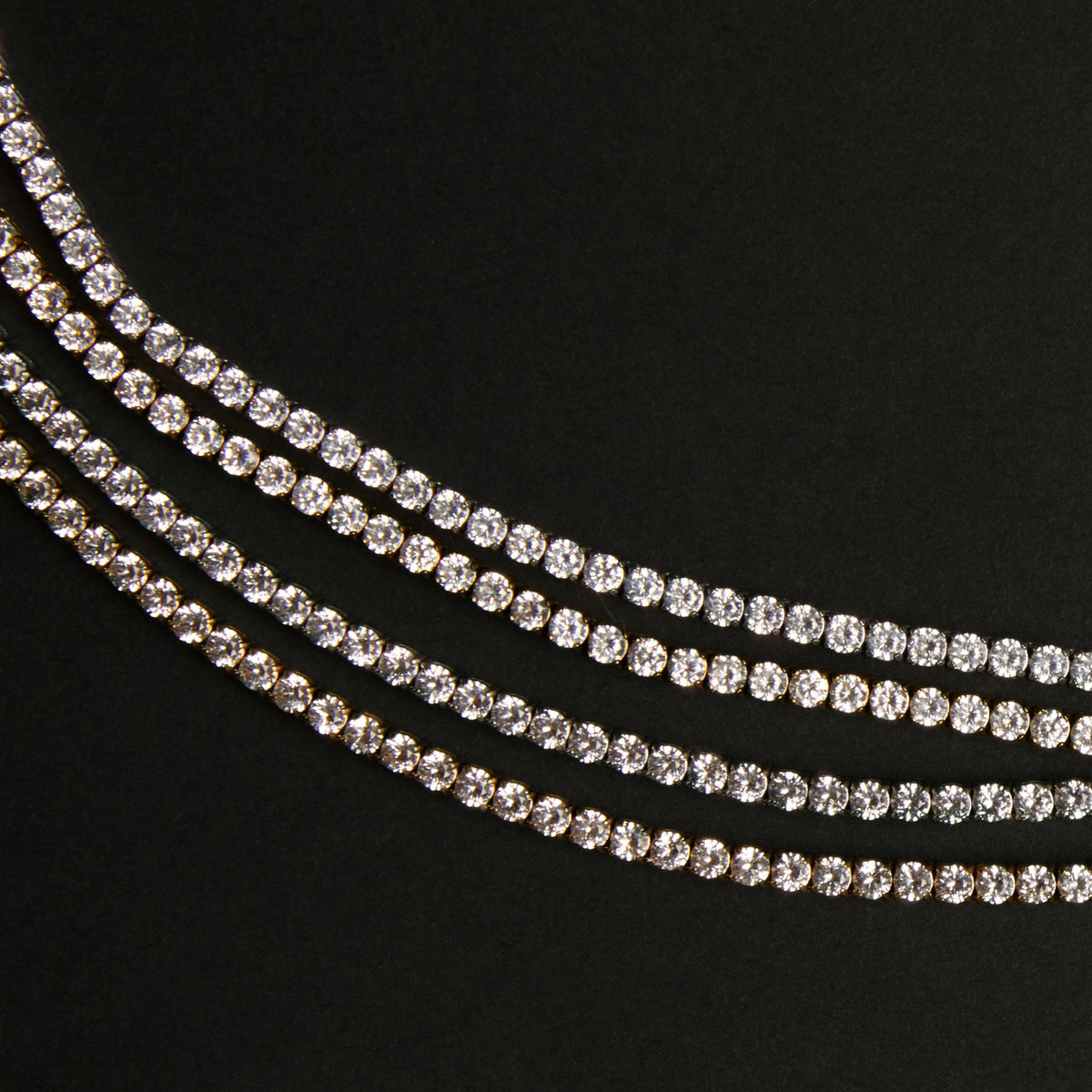 Three strands of white sapphire tennis bracelets on a black background