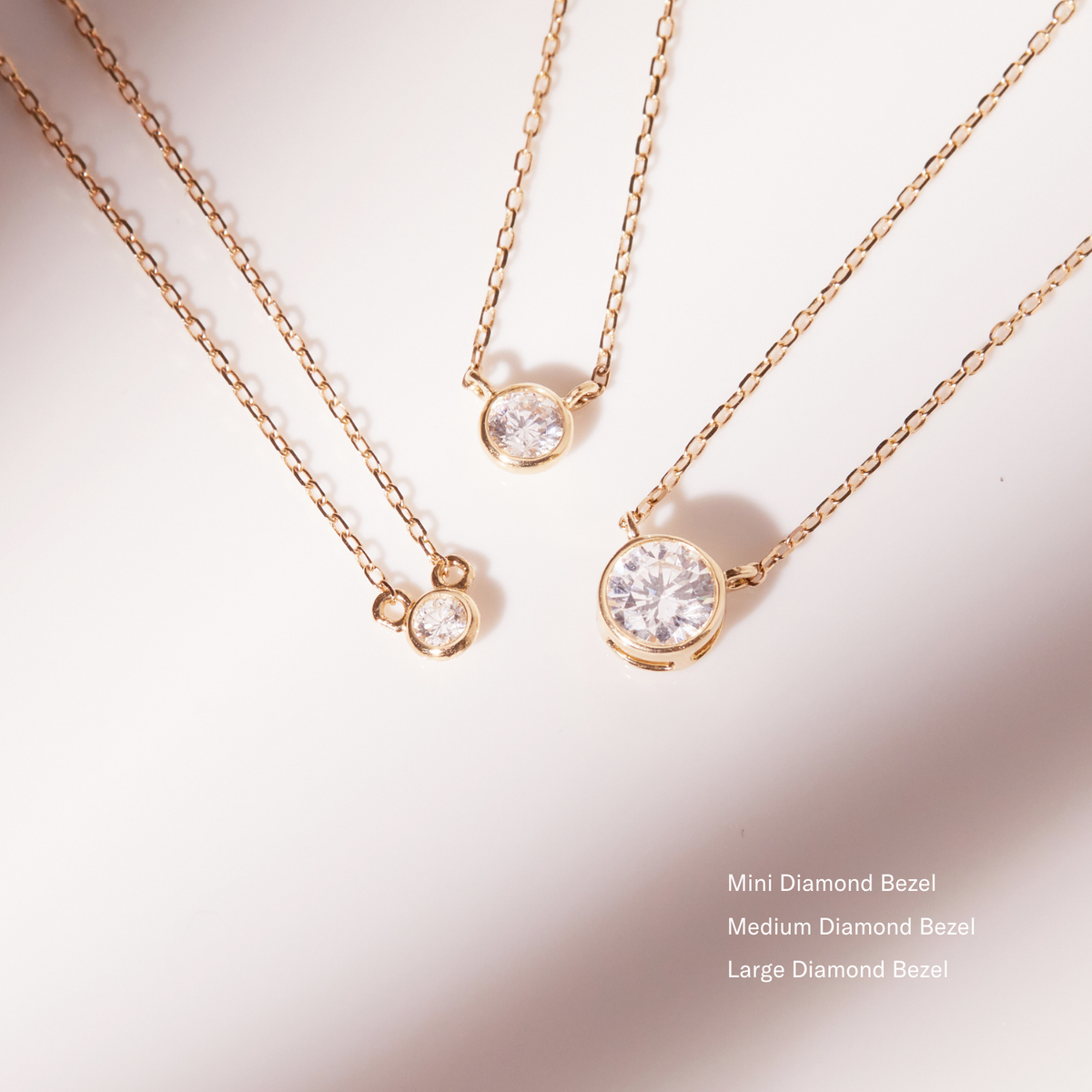 Model. Close up of three diamond bezel necklaces on white background