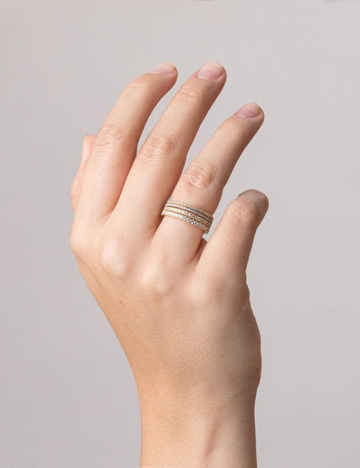 Model.  close up of hand wearing four gold rings 